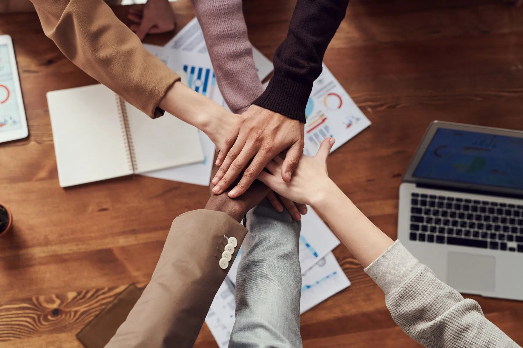 Manos de un equipo unidas sobre una mesa de trabajo