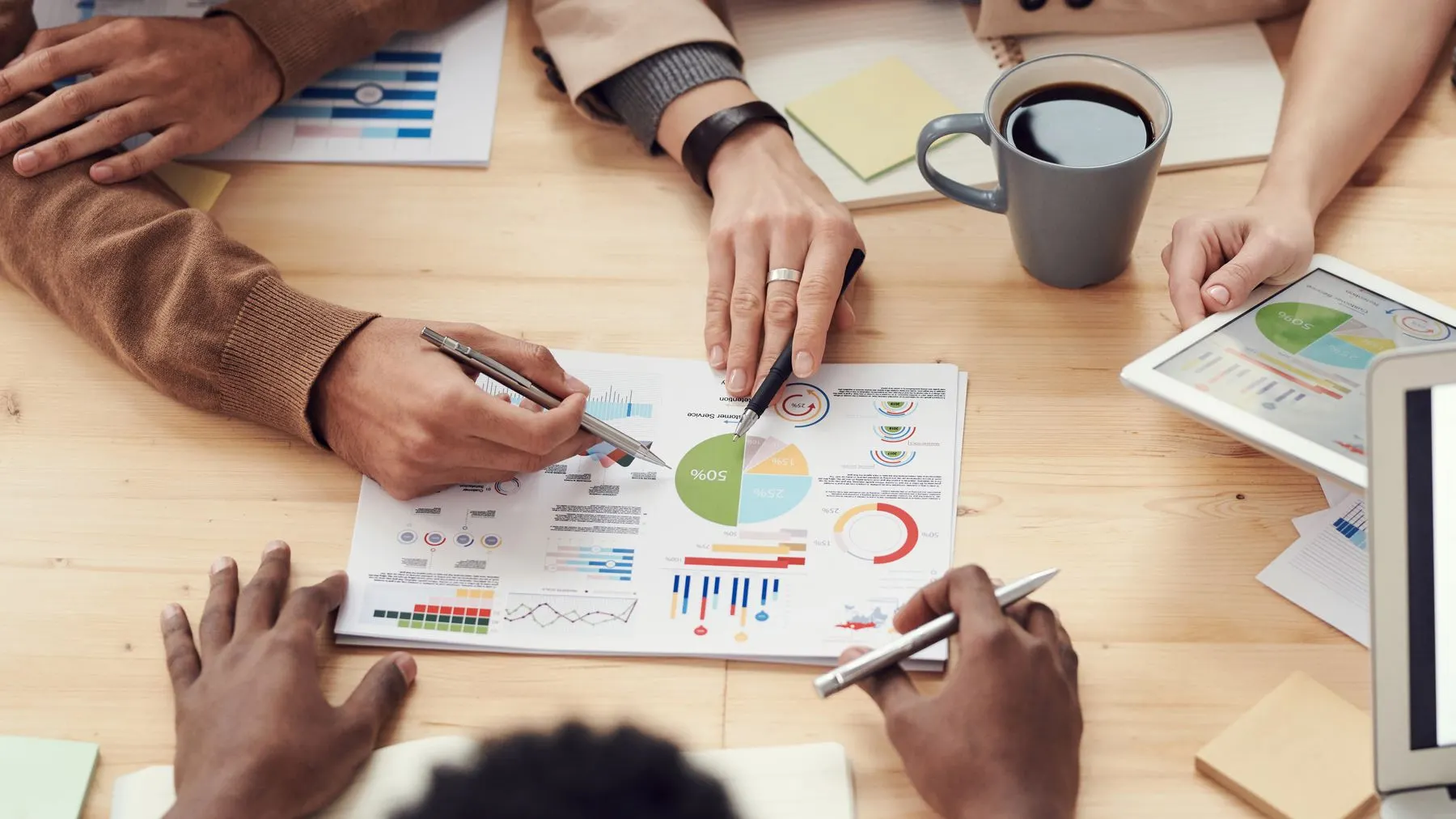 Informe con gráficos sobre la mesa mientras un equipo lo analiza